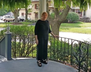 Bonnie Yates, 77, on the porch of her historic home in West Dundee, Illinois. The town is proposing a new taxing zone that will increase Yates’ property taxes by more than $1,100 per year. The building across the street from her is a law firm. They are not included in the SSA, which will save them an estimated $1,450 per year.